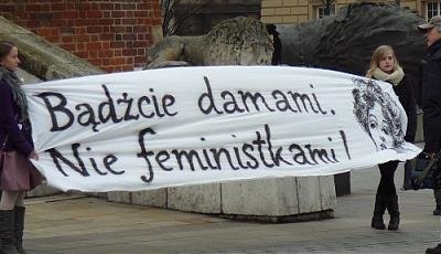 Dwie młode kobiety trzymają transparent z napisem bądźcie damami, nie feministkami