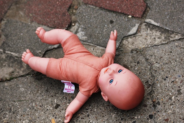 lalka przedstawiająca niemowlę leży na betonowym chodniku